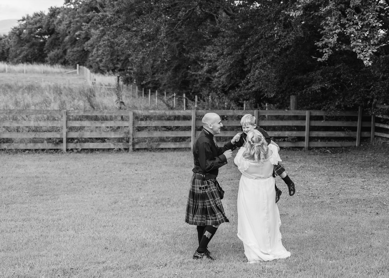 Black and white photo of couple dancing joyfully in outdoor garden setting.