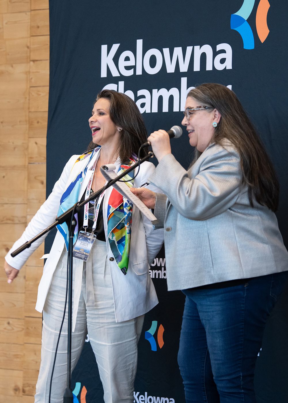 Two Kelowna Chamber staff  at networking event, one speaking into microphone - professional event photo by Tania Veitch.
