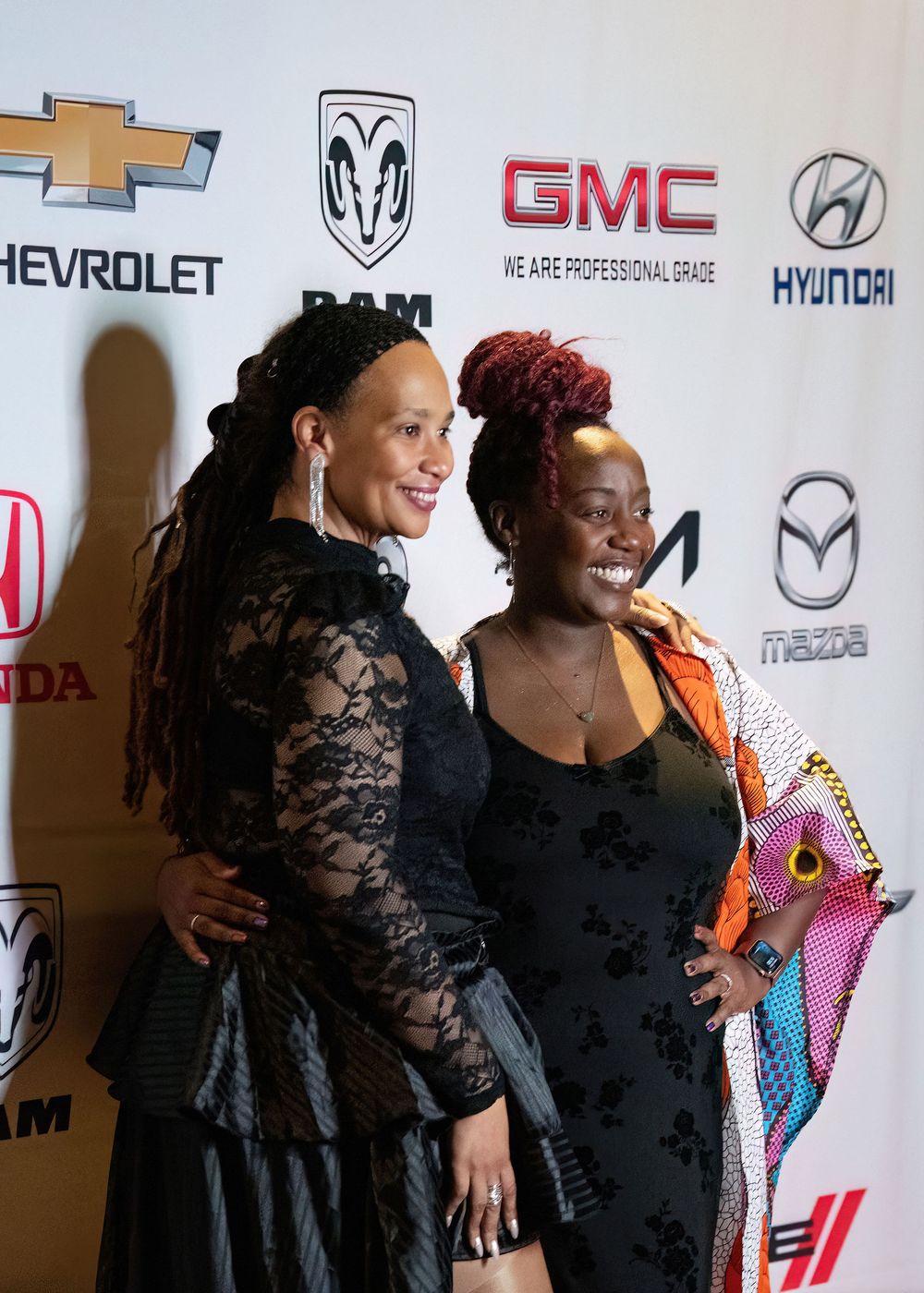 Two attendees smiling at a gala photo backdrop.