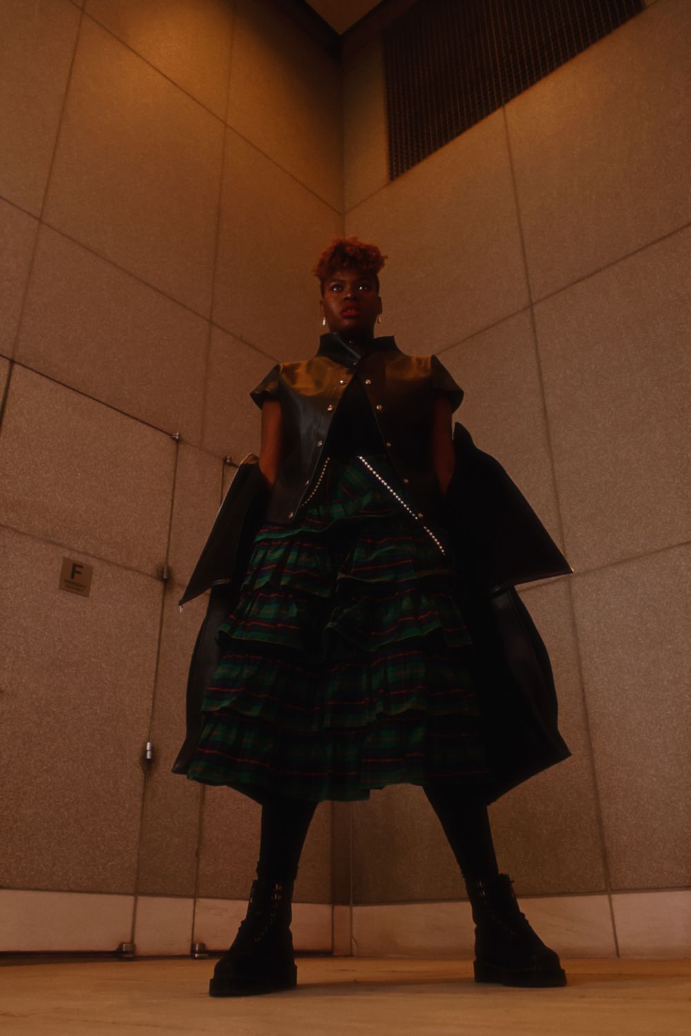 A sequence of four dramatic low-angle shots showing a figure in dark plaid clothing against a white wall.