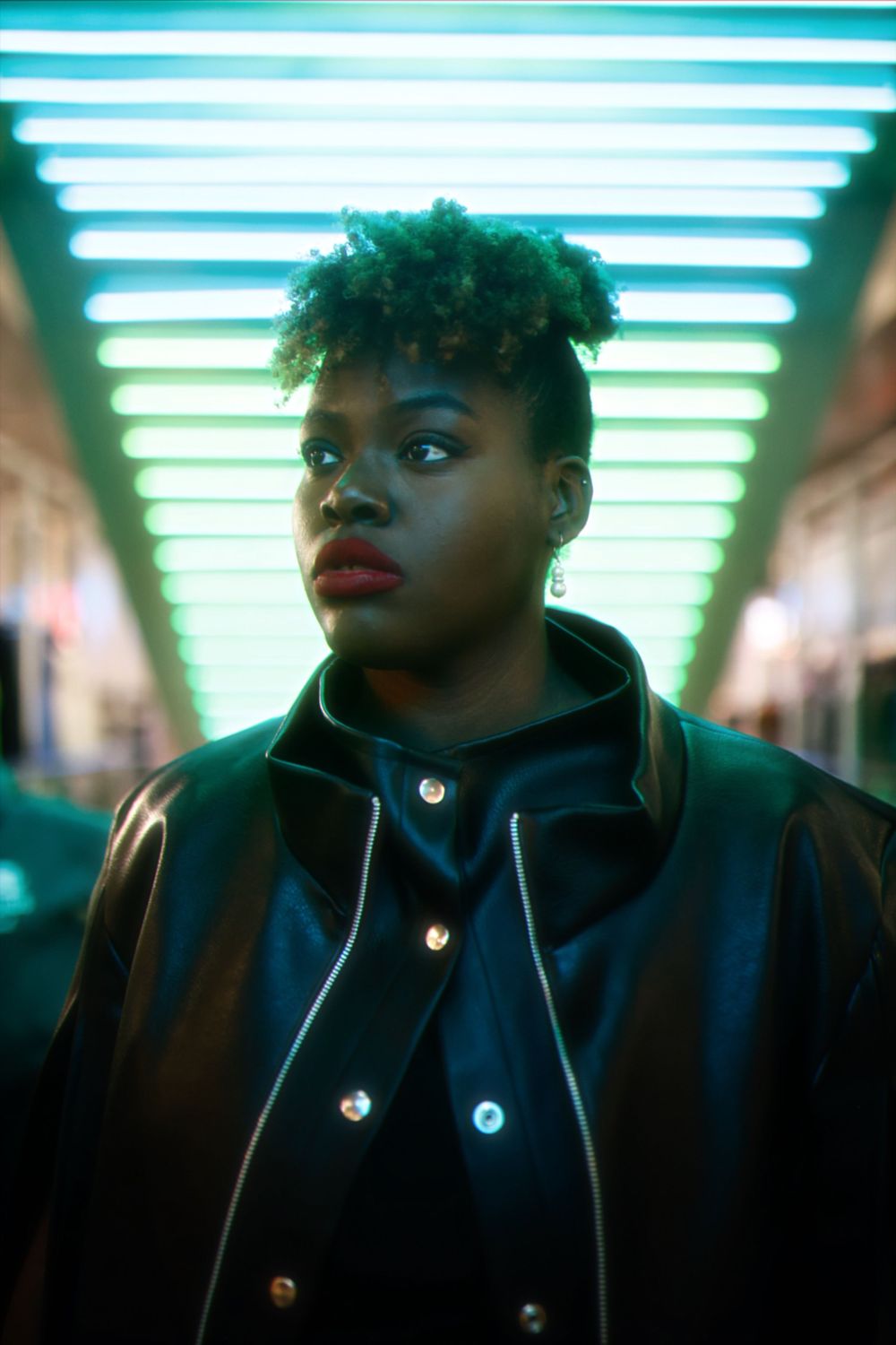 A sequence of similar portraits in dark lighting with blue-green fluorescent lights glowing overhead.