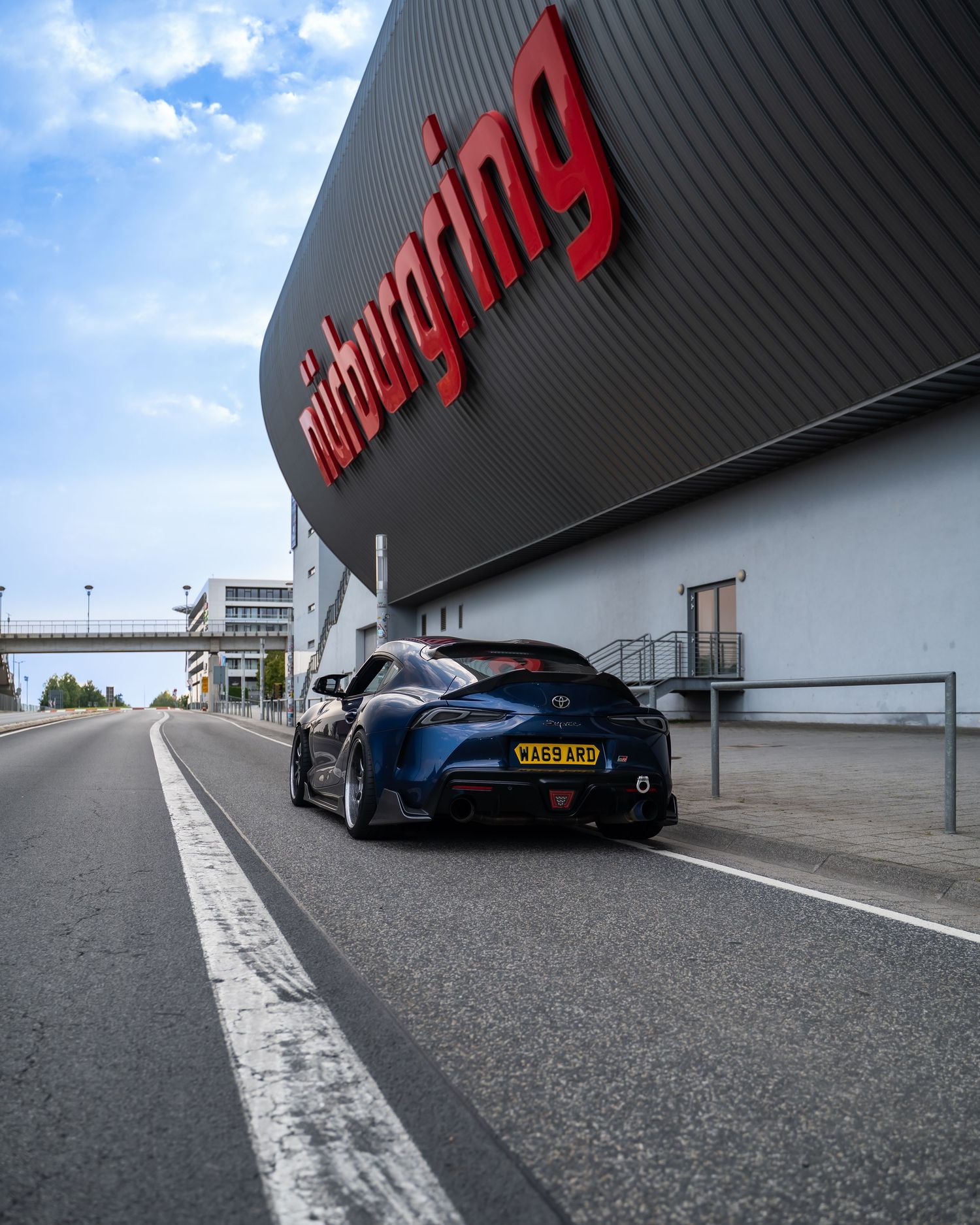 Wide angle view of modified sports cars parked along a curved building wall.