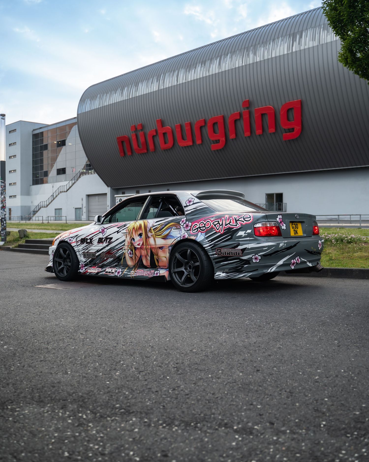 Custom wrapped performance cars lined up outside an industrial building.