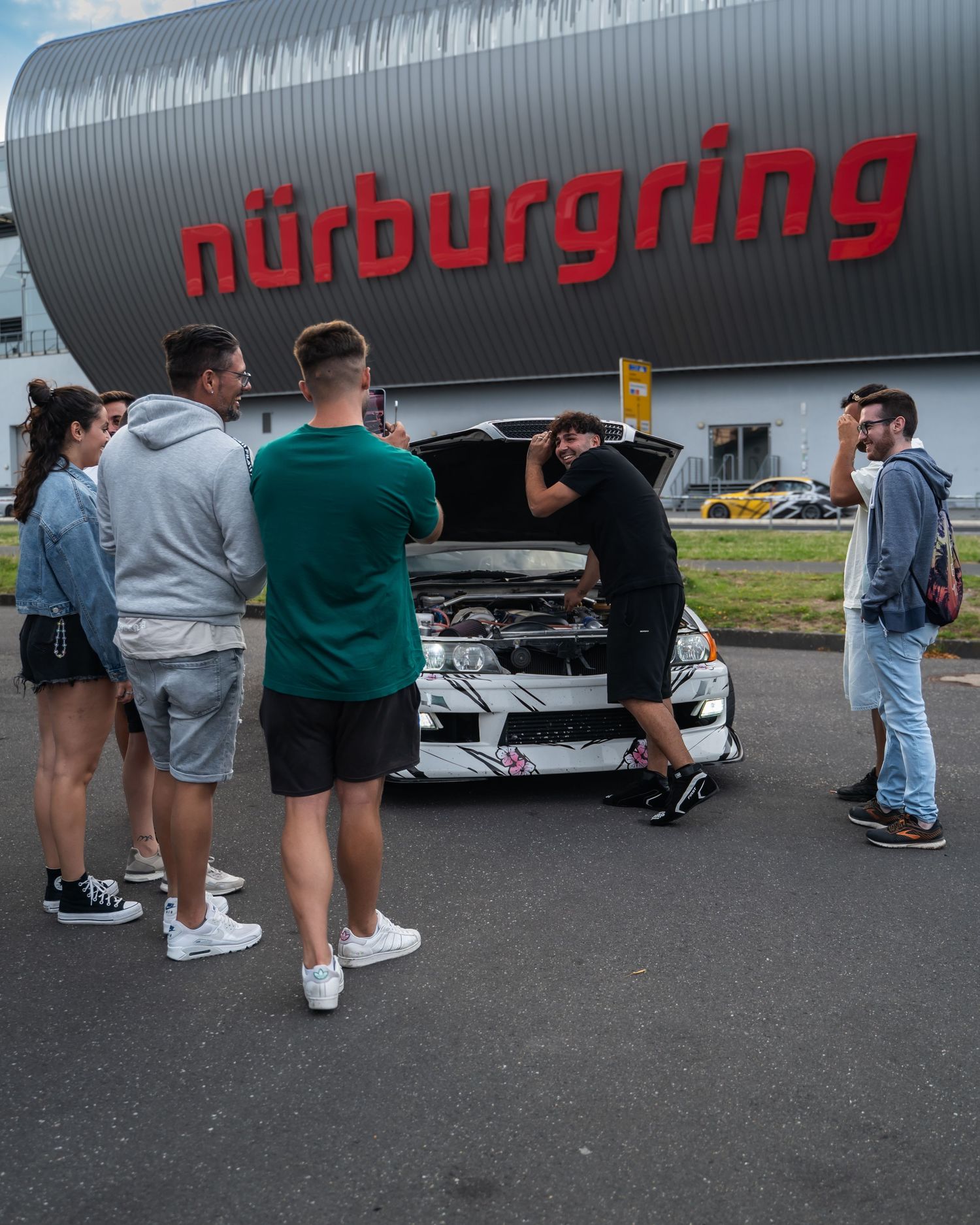 People gathered around parked cars outside the Nürburgring facility.