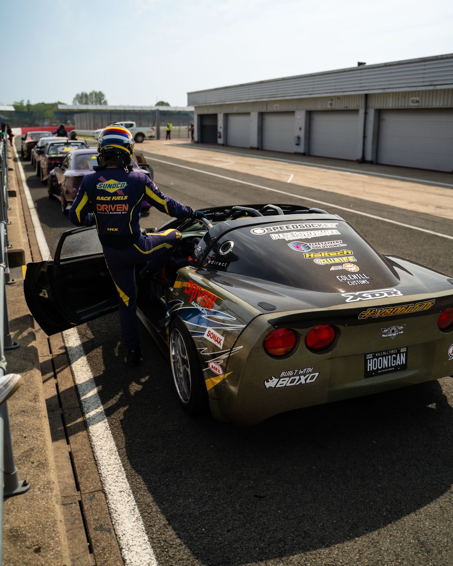 Modified black Corvette sports car with custom bodywork and red taillights shown from multiple rear angles on a racetrack.