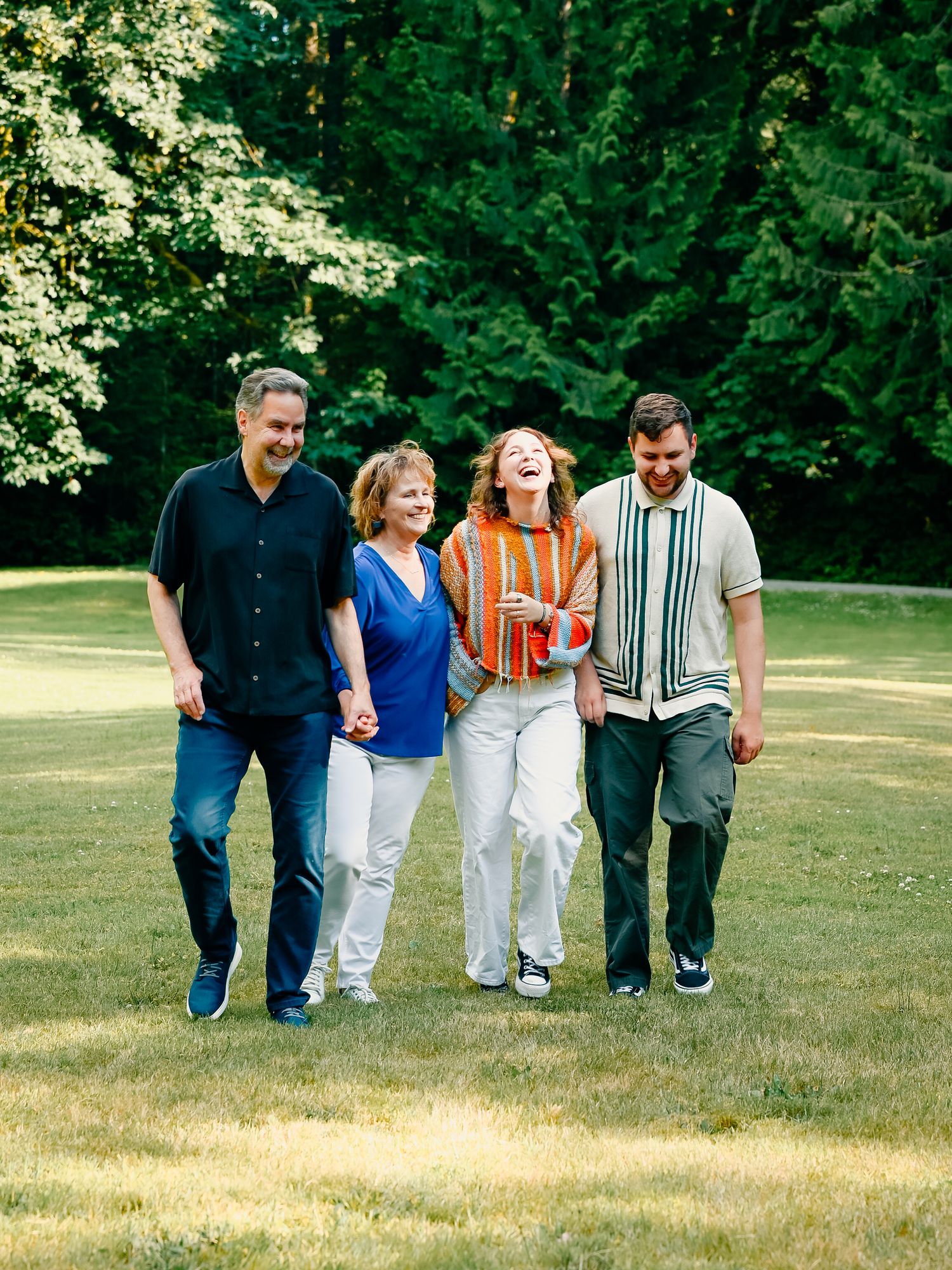 A group of people walking in sync on a grassy field with sunlit trees in the background.