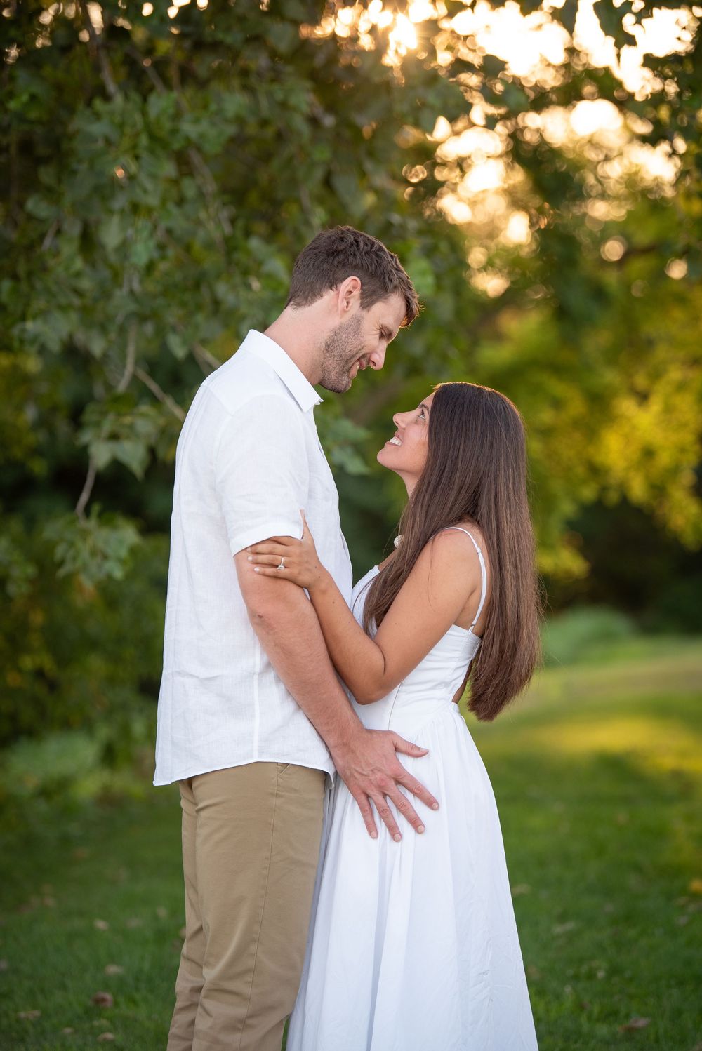 Sweet candid moment between couple dressed in white during sunset photography session.