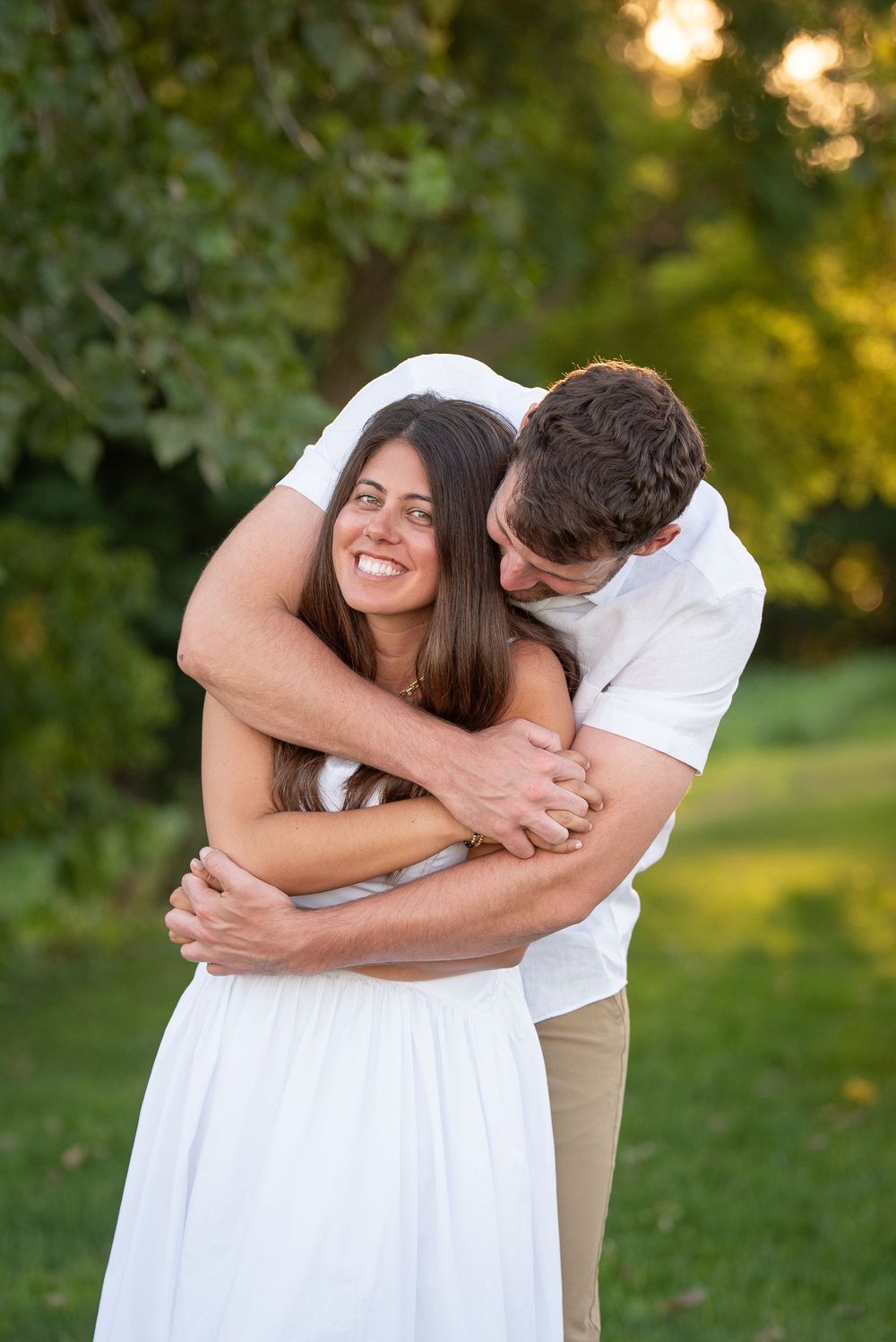 Joyful couple shares laughs and embraces during outdoor summer photoshoot.