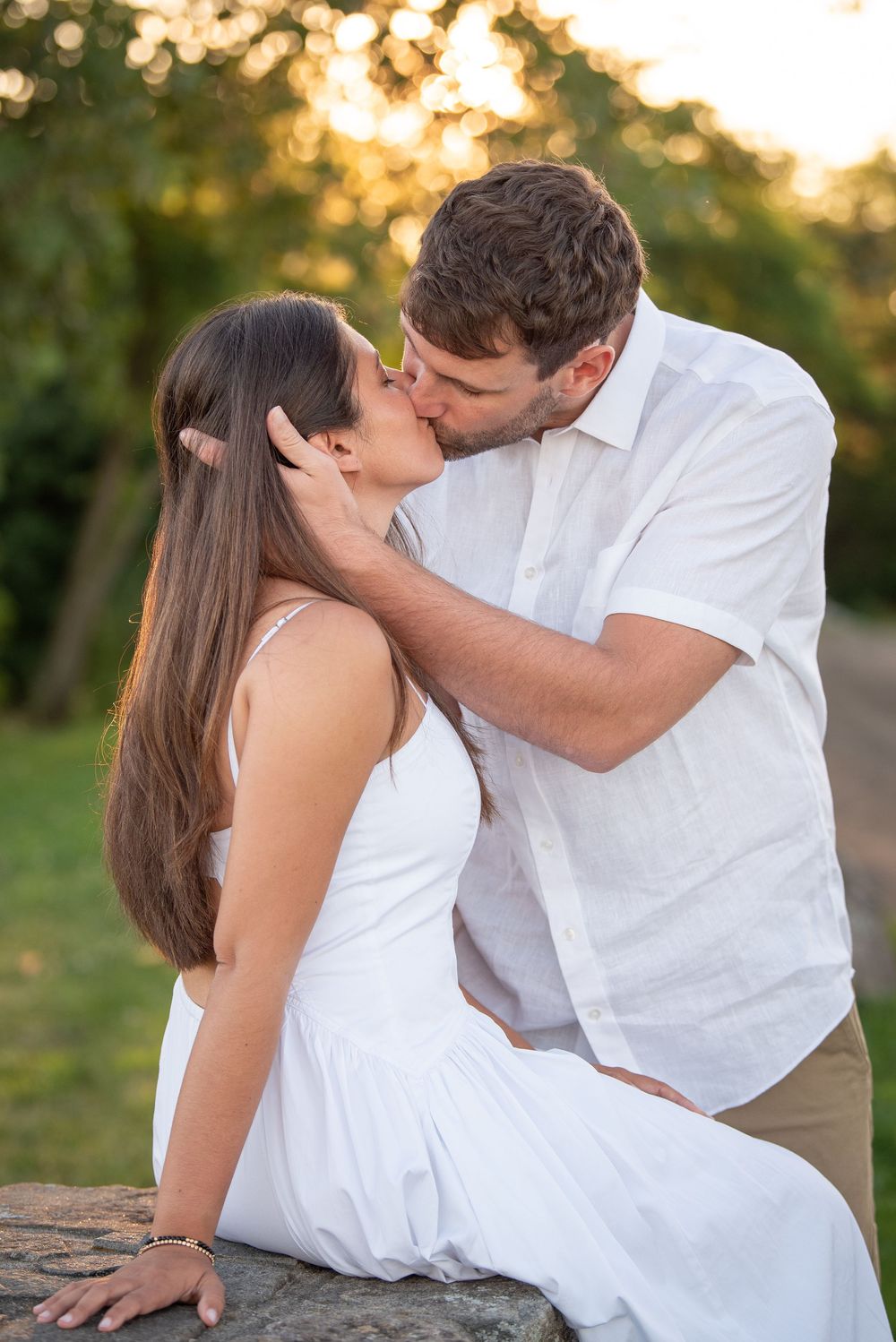 Intimate moment between couple sitting on rock during golden hour photoshoot.