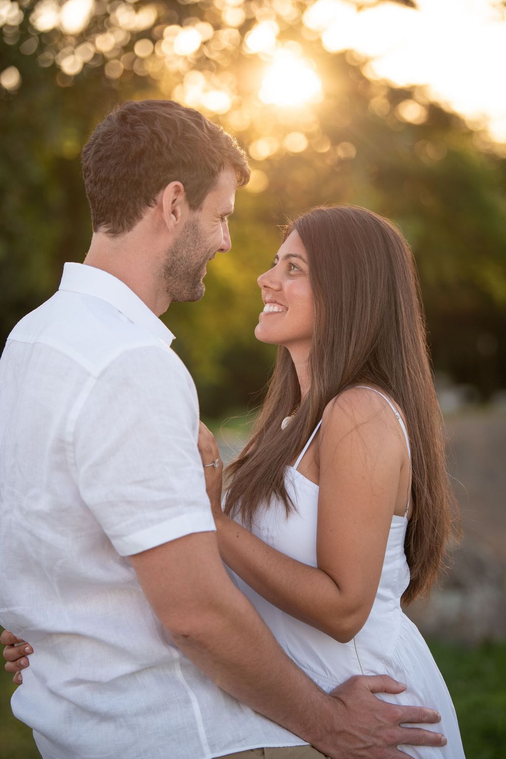 Couple laughs together during sunset engagement photo session in park setting.
