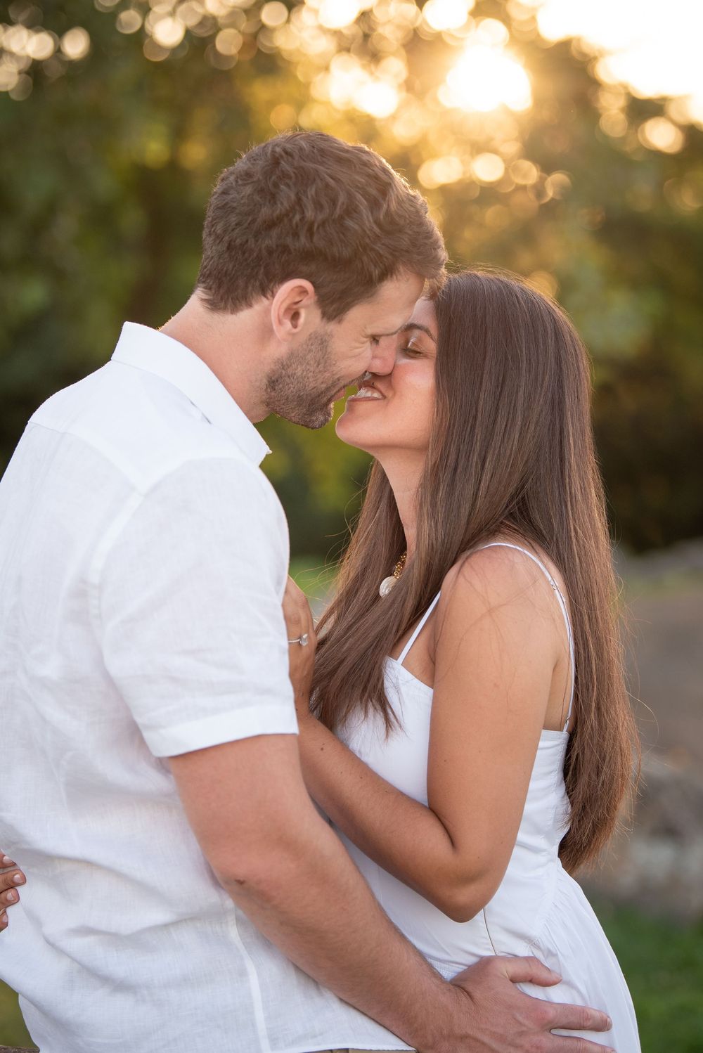 Intimate portrait of couple in white clothing against blurred nature background.