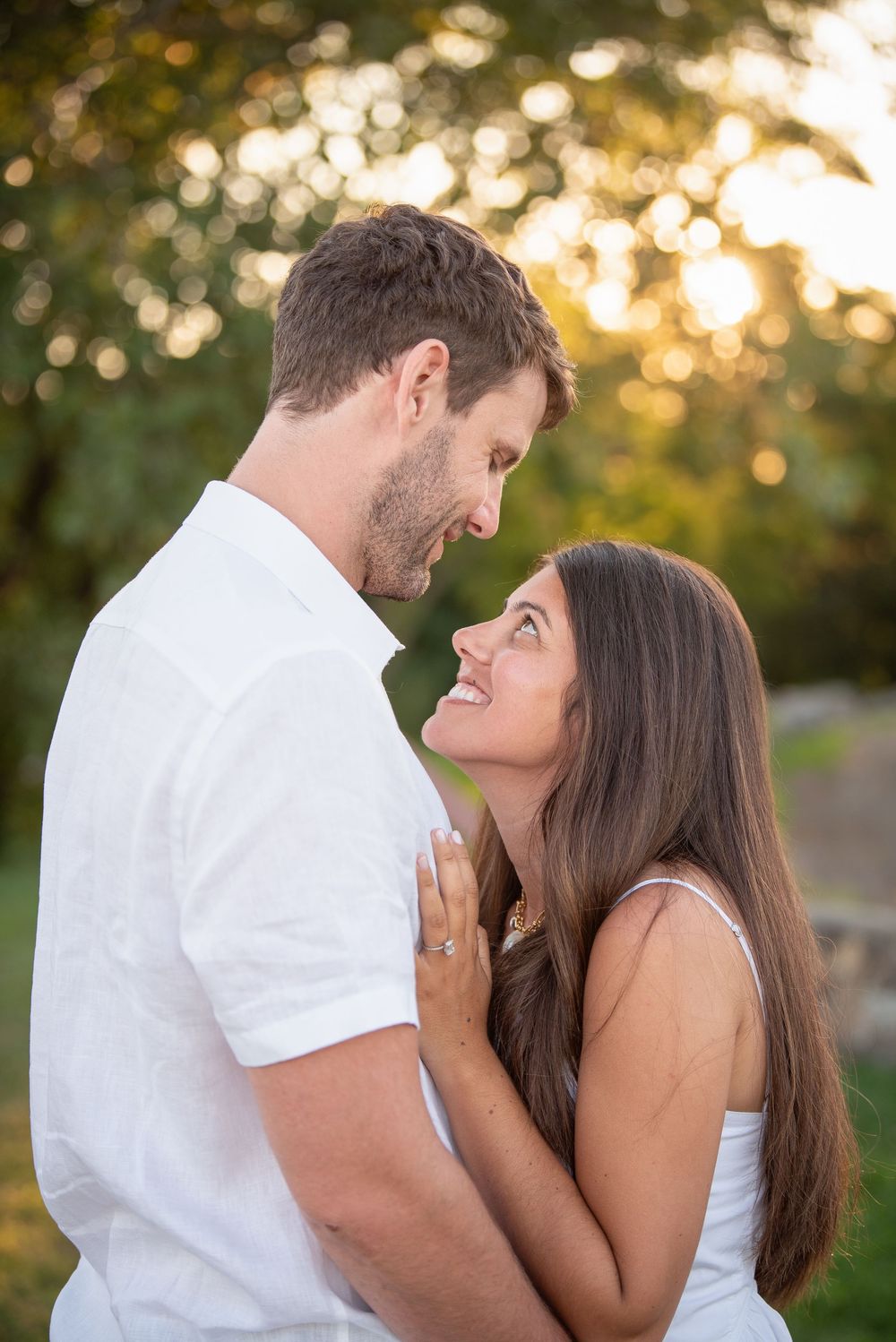 Romantic outdoor portrait of couple in white clothing during golden hour.
