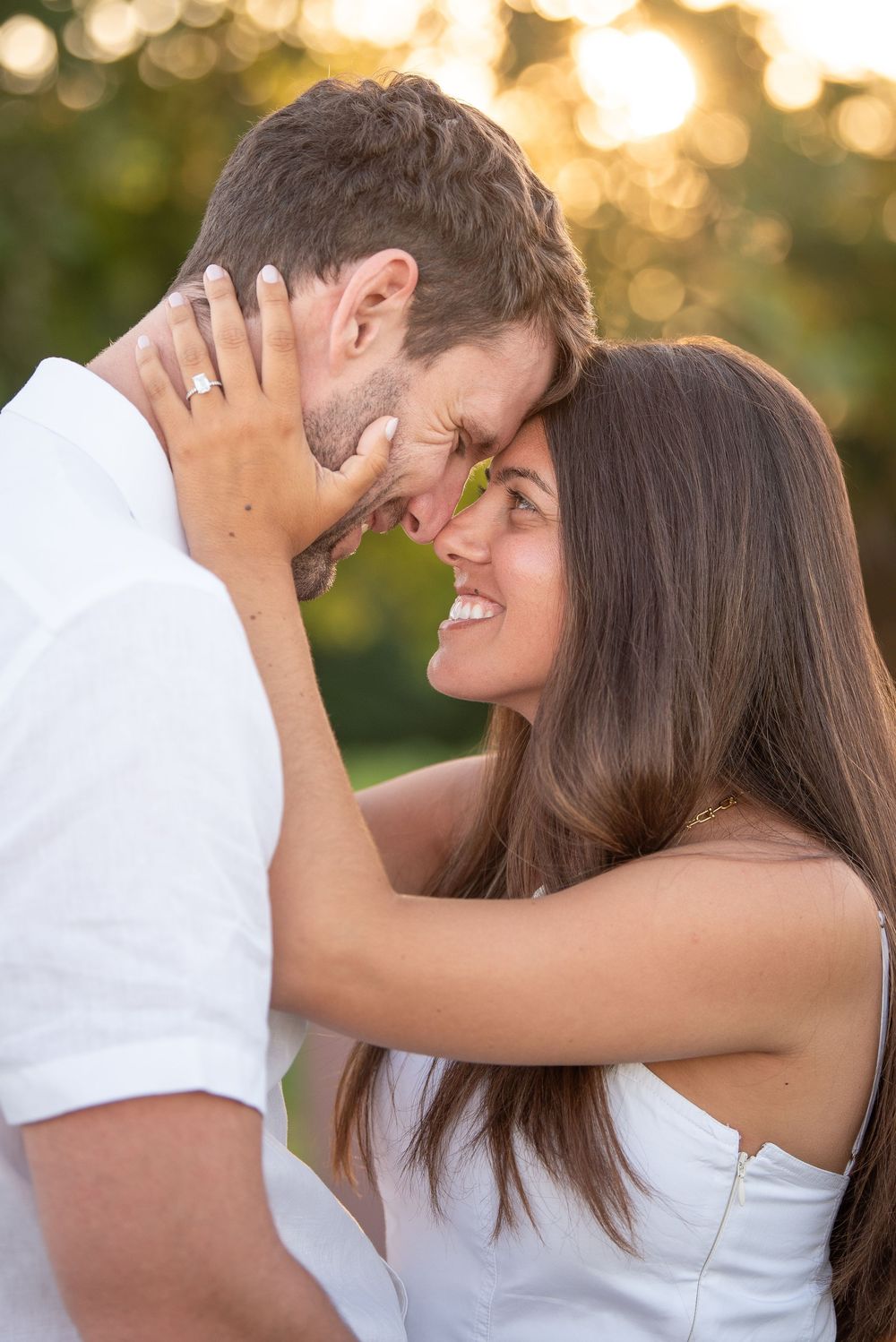 Tender moment between couple with sunset bokeh in background.