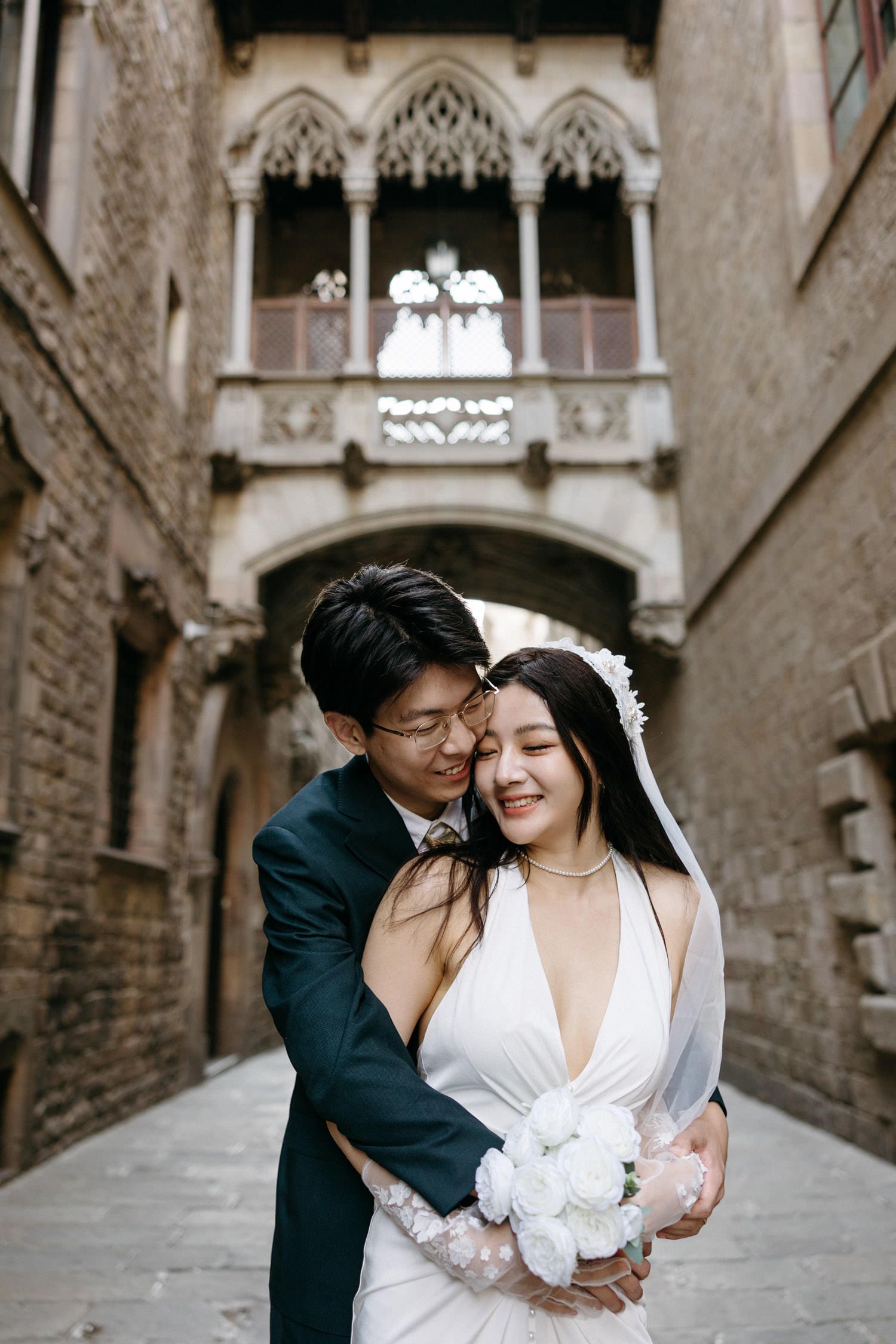 Newlyweds share intimate moments in a Gothic Quarter alleyway with stone architecture.