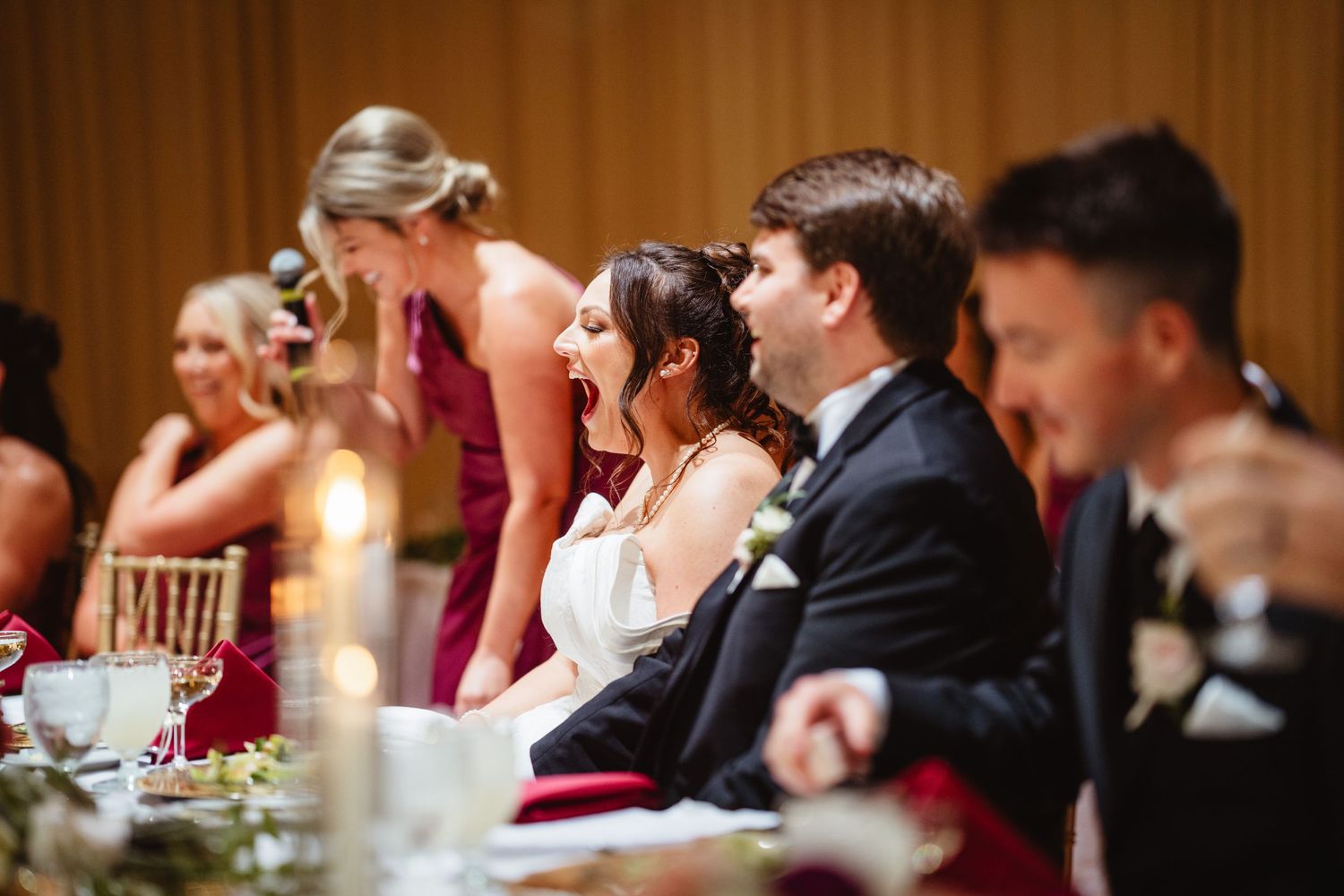 Wedding guests seated at an elegant reception dinner table with candlelight and glowing ambiance.