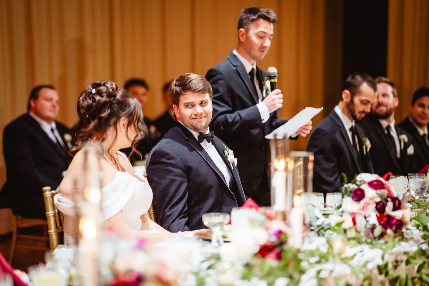 Wedding reception table decorated with red and white floral centerpieces in an elegant ballroom setting.