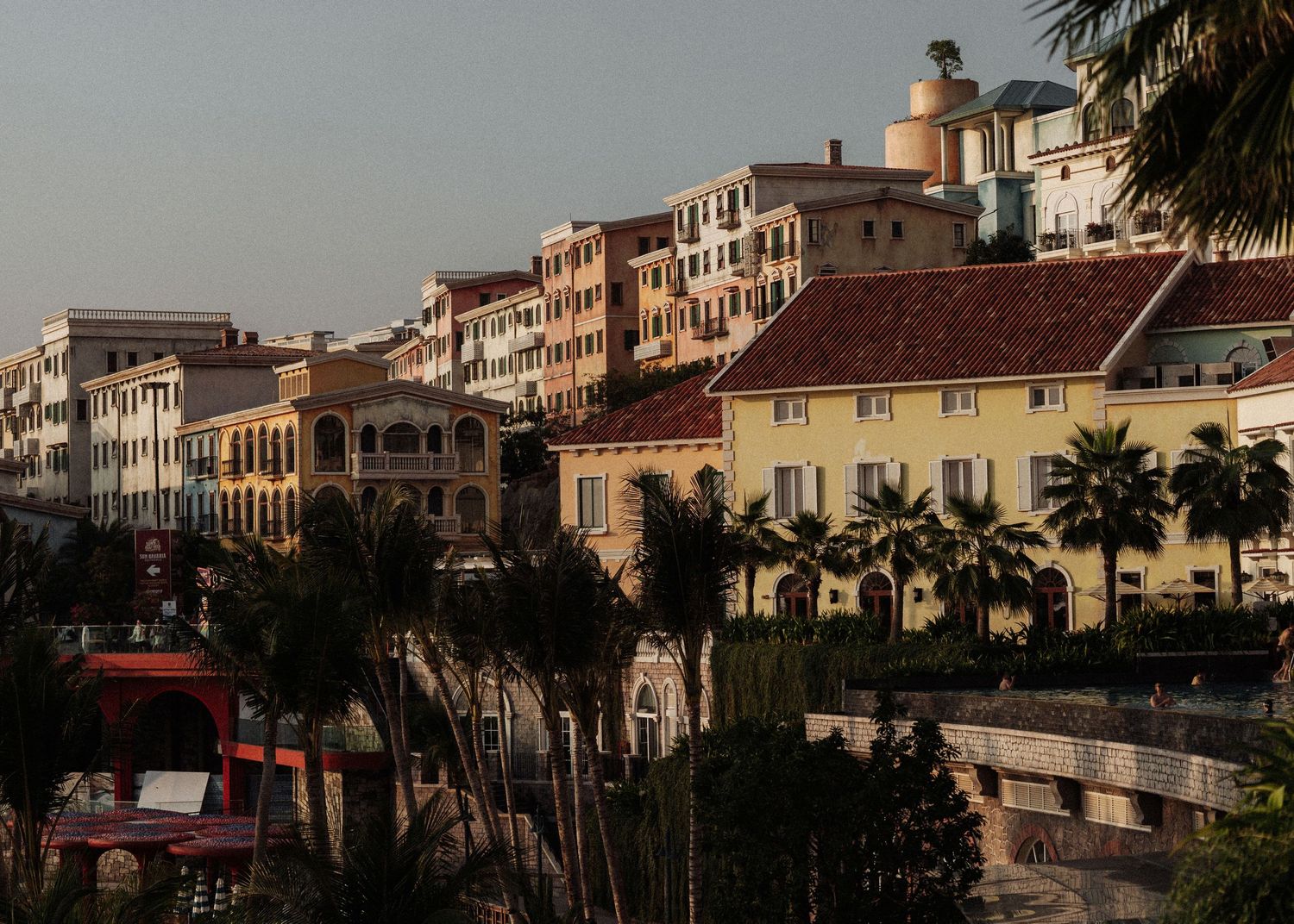 Colorful Mediterranean-style buildings with palm trees at golden hour.