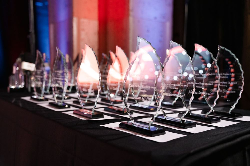 Prancing glass horse sculptures displayed in sequence on illuminated shelves against a dark background create an artistic gallery.