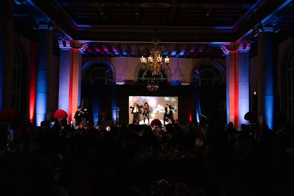 Wedding reception venue with blue and red uplighting illuminating elegant chandeliers and guest tables.