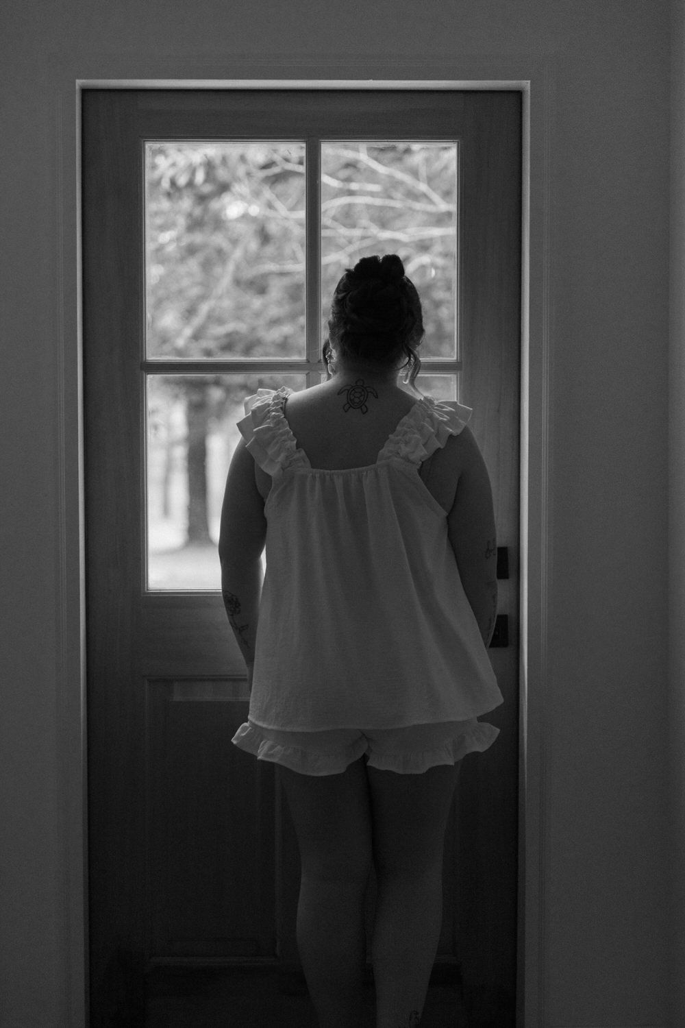 Bride looking at ceremony spot through a window on her north georgia wedding day