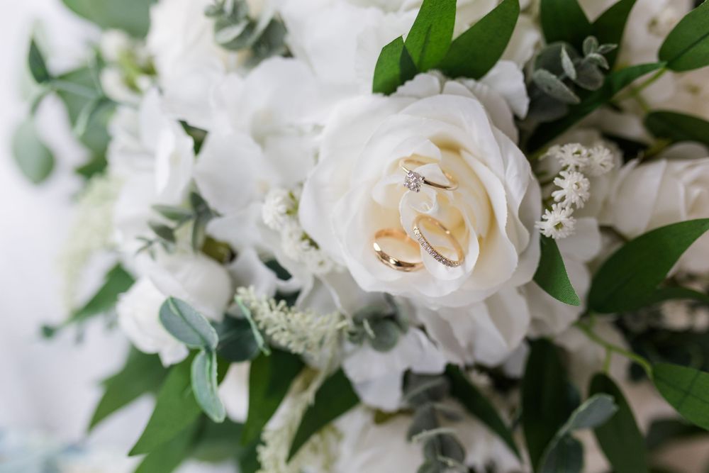 Fresh white roses and greenery arranged in an elegant wedding bouquet against a light background.
