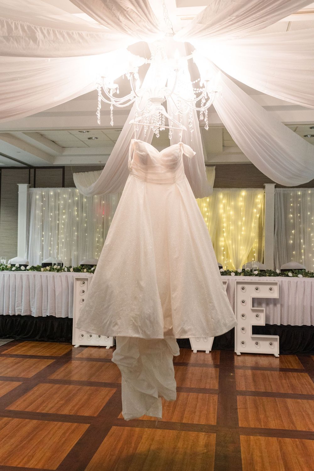 A sequence of dress display shots showing different white wedding gowns against wooden flooring and draped fabric decor.