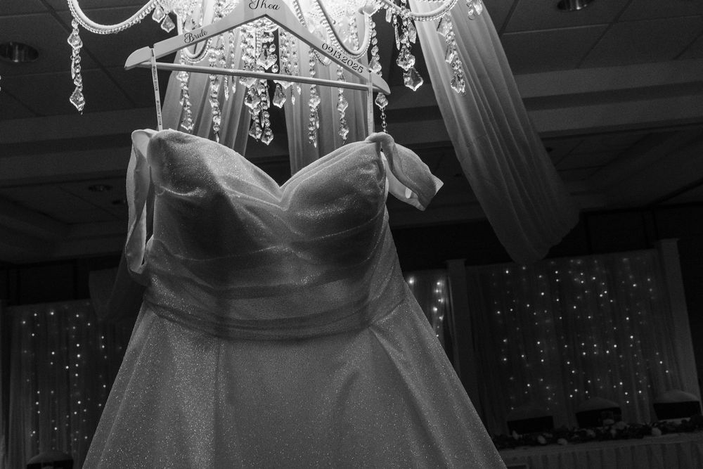 Multiple wedding dresses and gowns are beautifully displayed on hangers in a bridal shop fitting room.