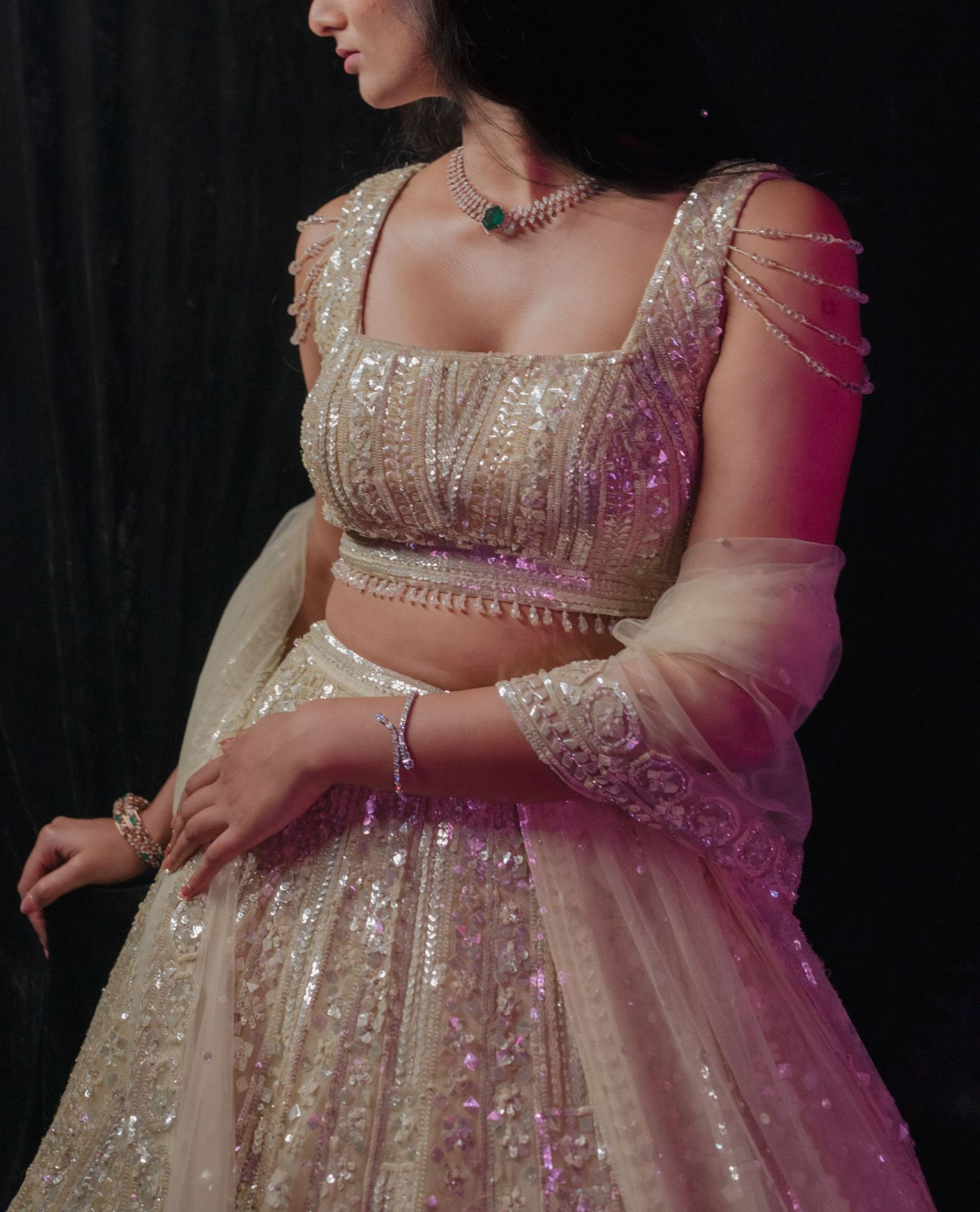 Cropped view of an embellished cream lehenga dress with sparkly sequins and sheer fabric details.