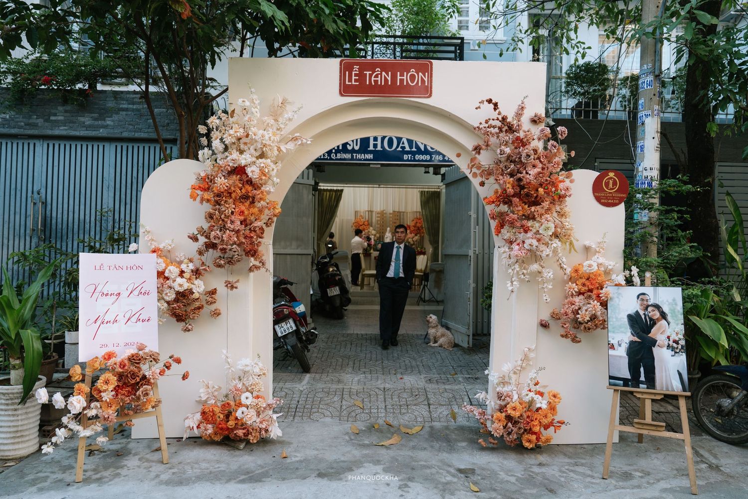 Floral arch entrance decorated with orange and pink blooms for a Vietnamese Le Tan Hon engagement ceremony.