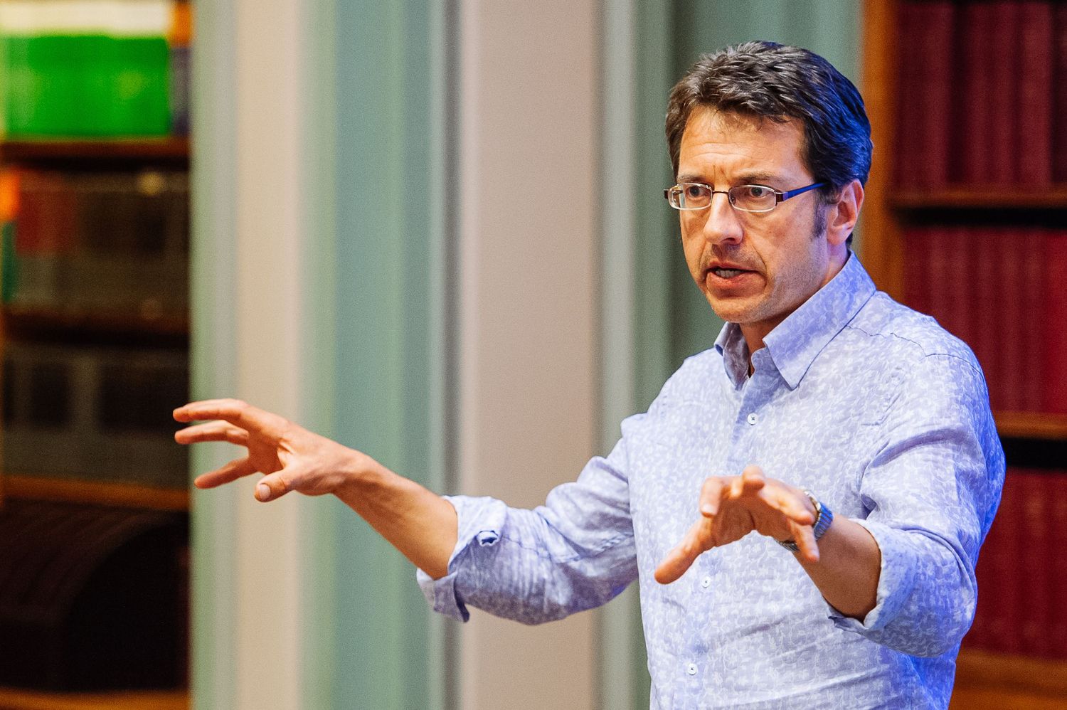 Speaker gesturing while giving presentation in conference setting.