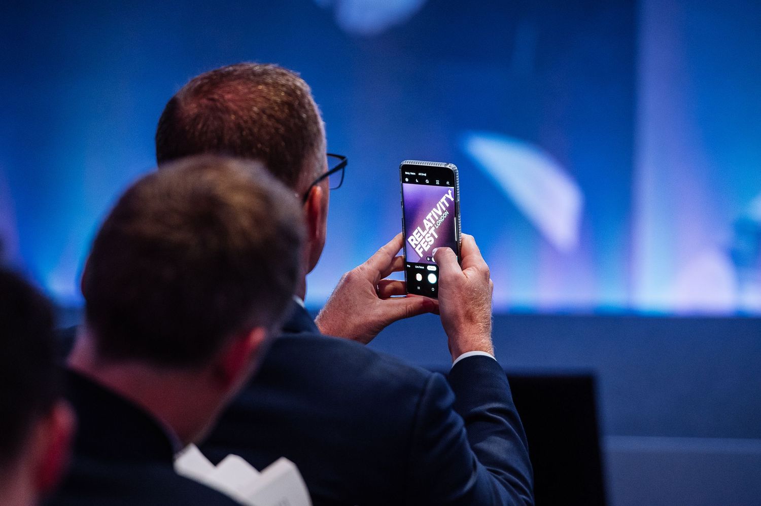 Audience members take photos with phones at professional conference.