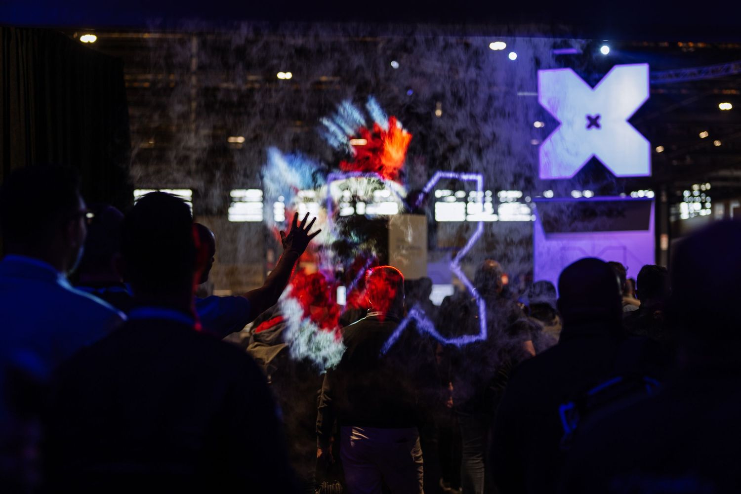 Conference venue with colorful stage lighting and audience silhouettes.