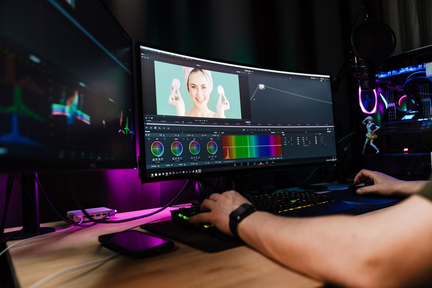 Multiple dark computer monitors with RGB lighting displays arranged across a black desk in a dimly lit gaming setup.