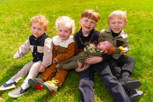 Group of young children playing and laughing together on bright green grass.