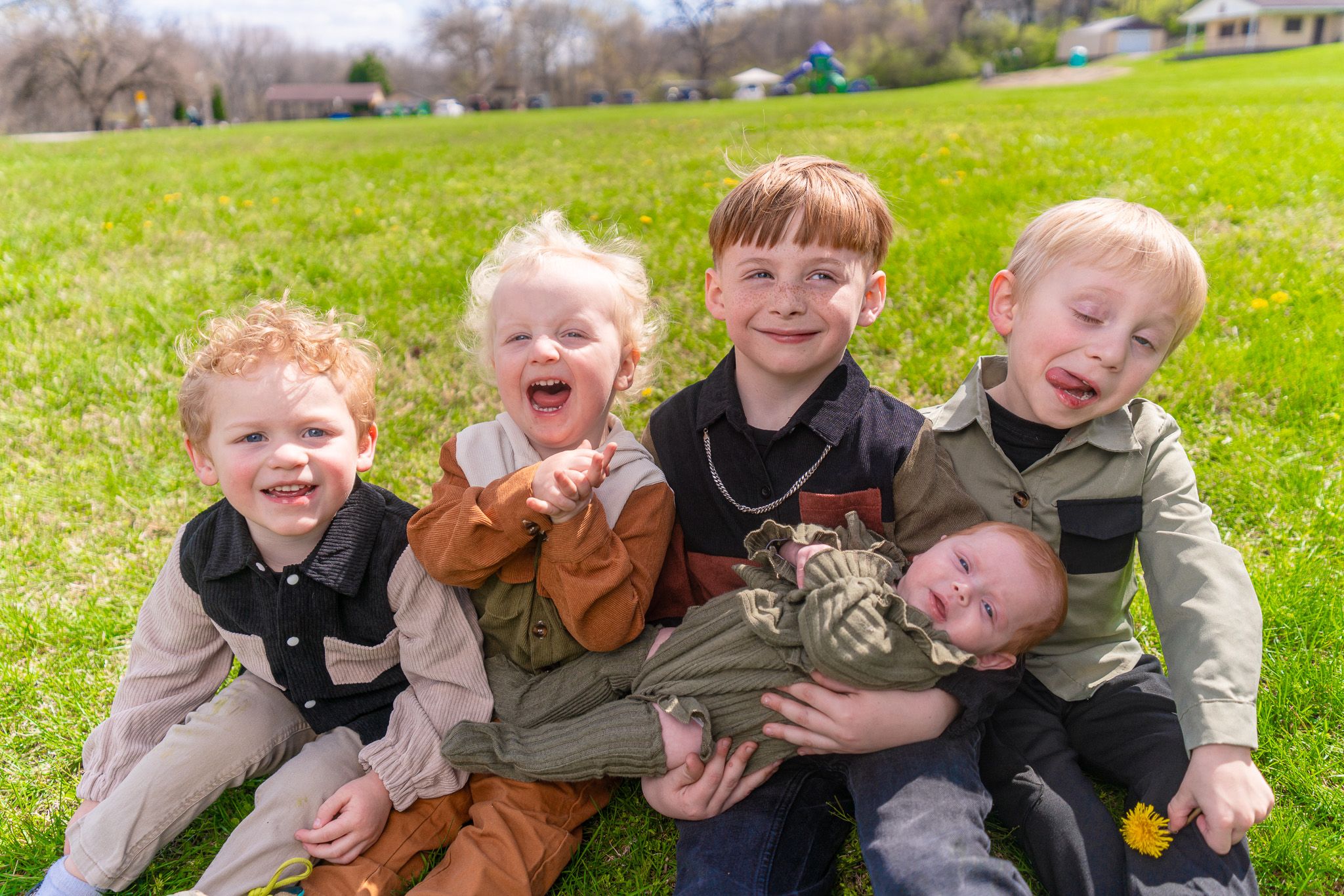Children having fun and being silly while posing together on grass.