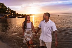 A couple strolls along the beach during a vibrant purple and orange sunset.