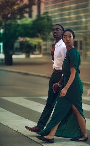 Two people walk together in coordinated outfits along an urban sidewalk.