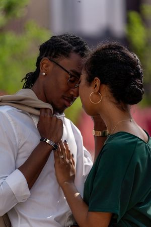 A couple shares a tender moment outdoors in formal attire.