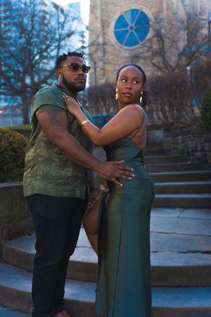 A couple shares an intimate dance moment outdoors at dusk near urban architecture.