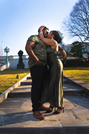 A couple dances together on concrete steps during sunset with urban buildings in the background.