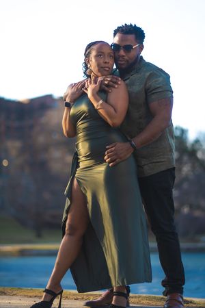A couple shares a romantic dance moment near a waterfront during golden hour.