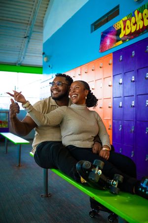 Two people having fun while roller skating in a vibrant indoor space with colorful lockers.