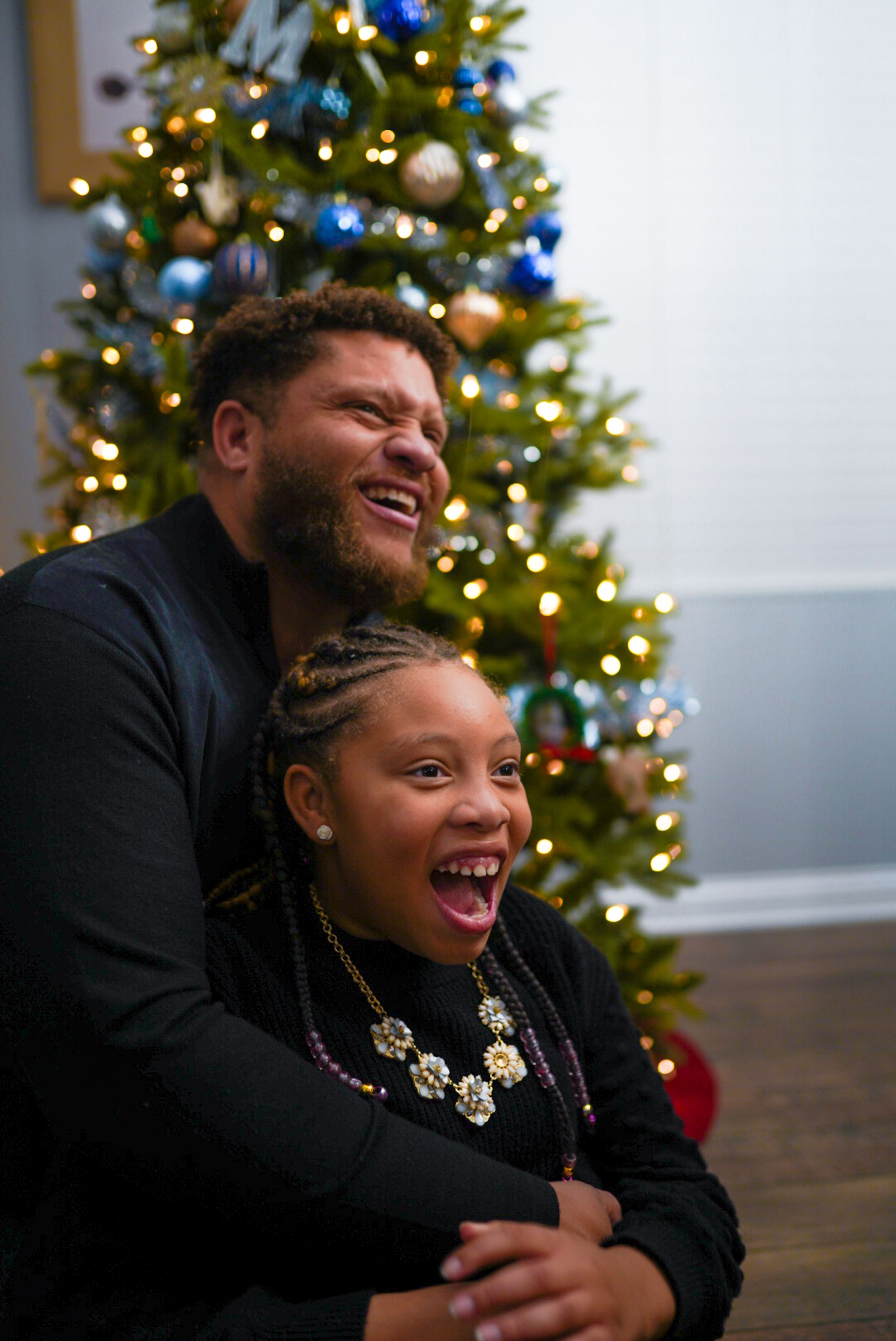 Joyful moment captured in front of a decorated Christmas tree with blue ornaments.