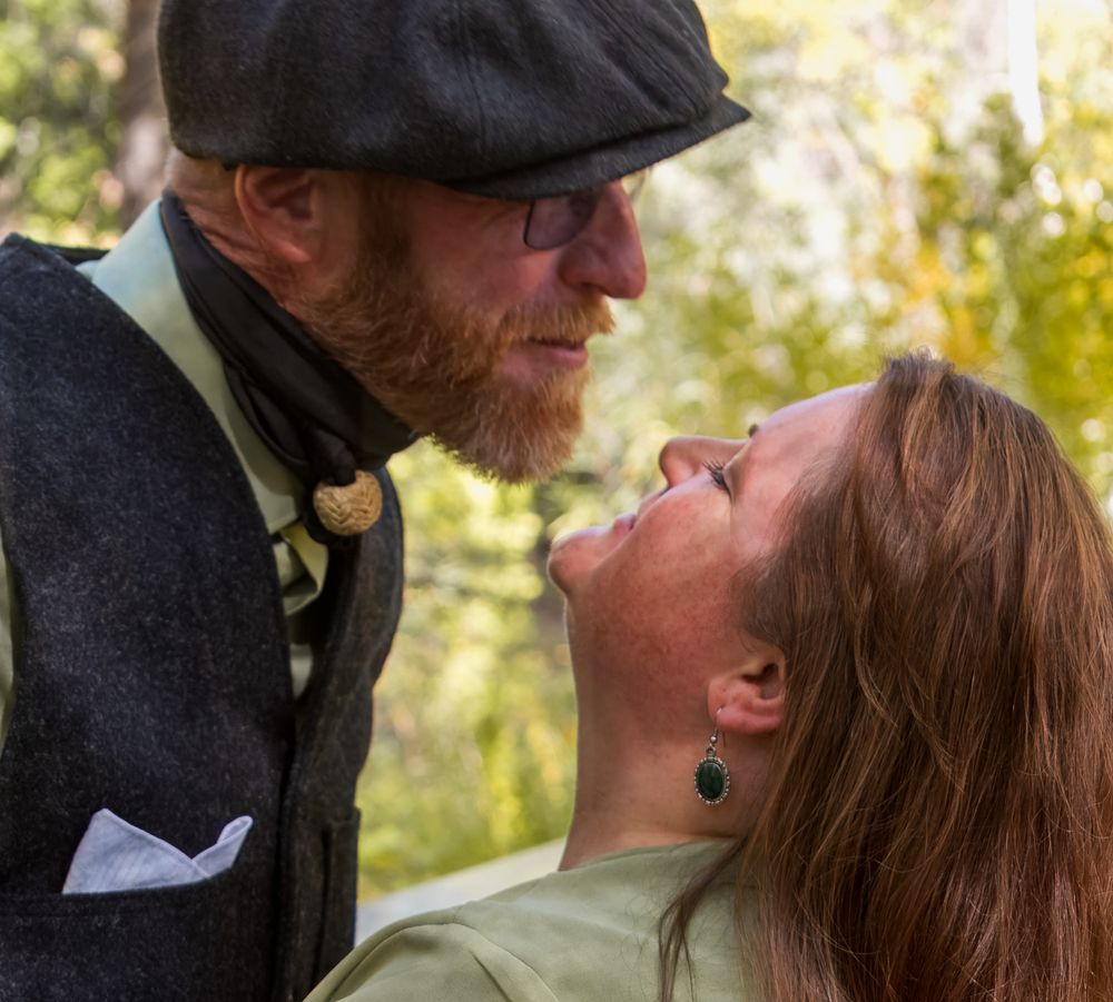 A photo showing a couple embracing and kissing in a natural outdoor setting.