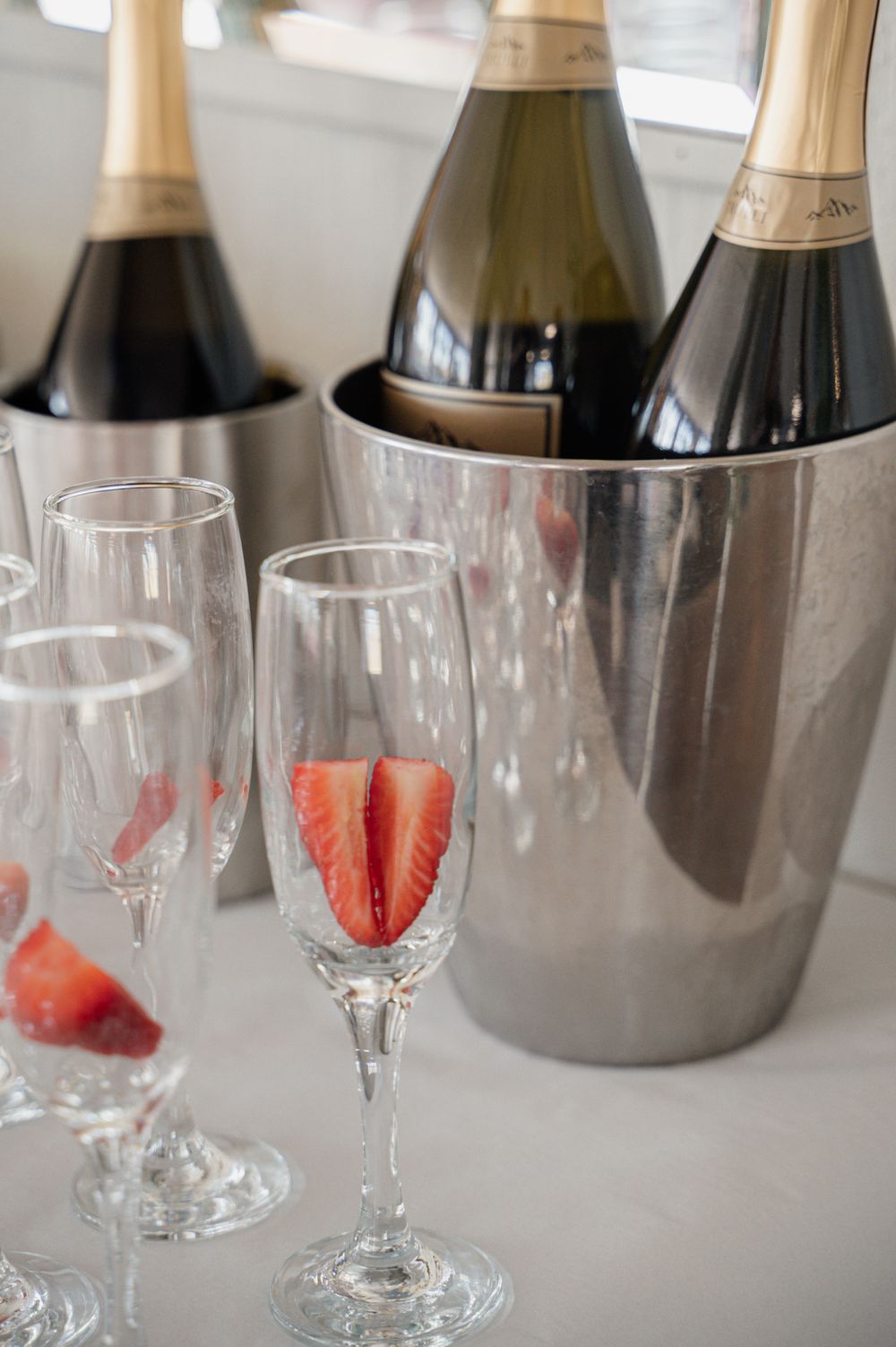 Champagne bottles in silver ice buckets with strawberry-garnished flutes.