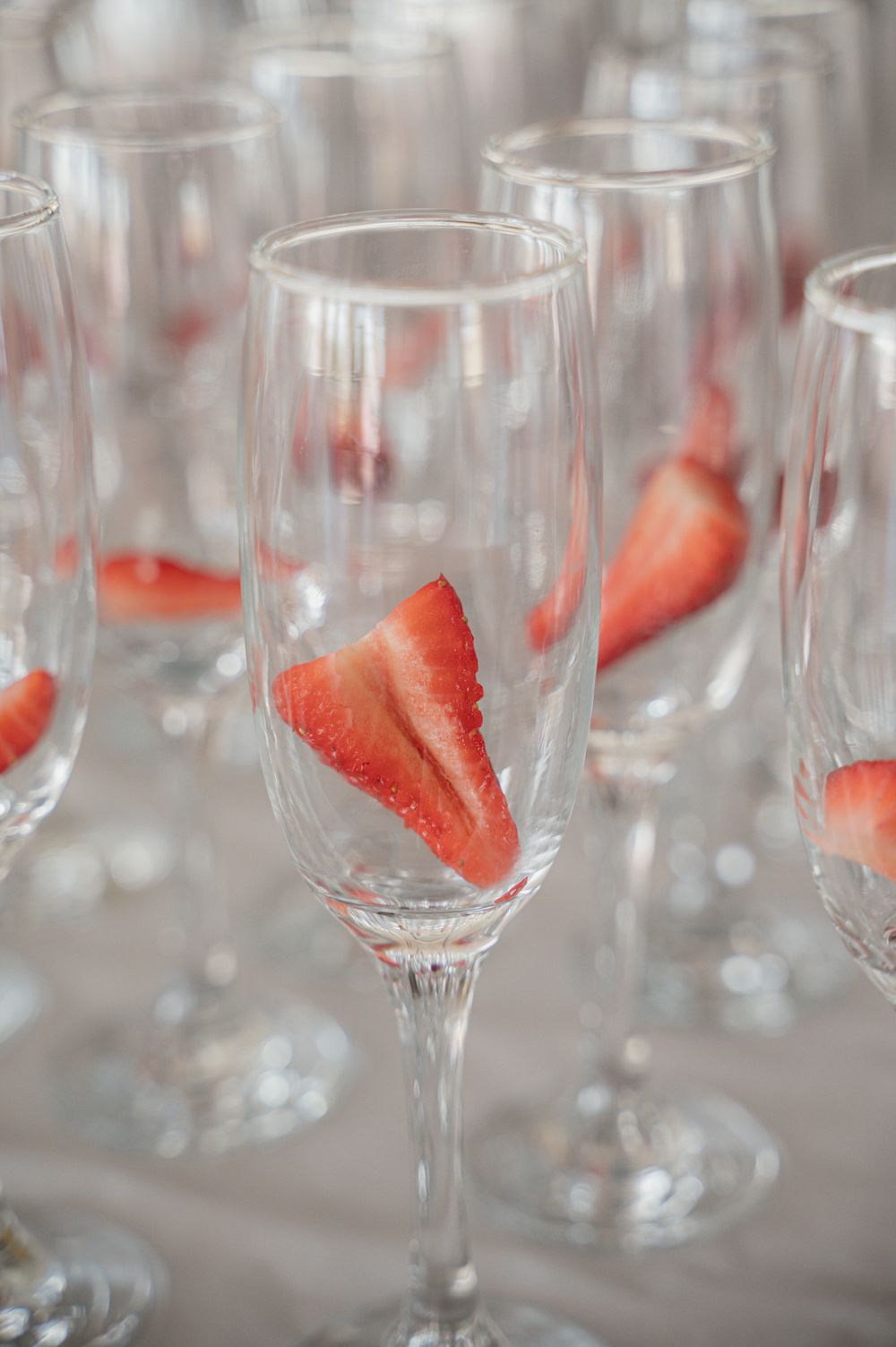 Crystal champagne flutes garnished with fresh strawberry slices.