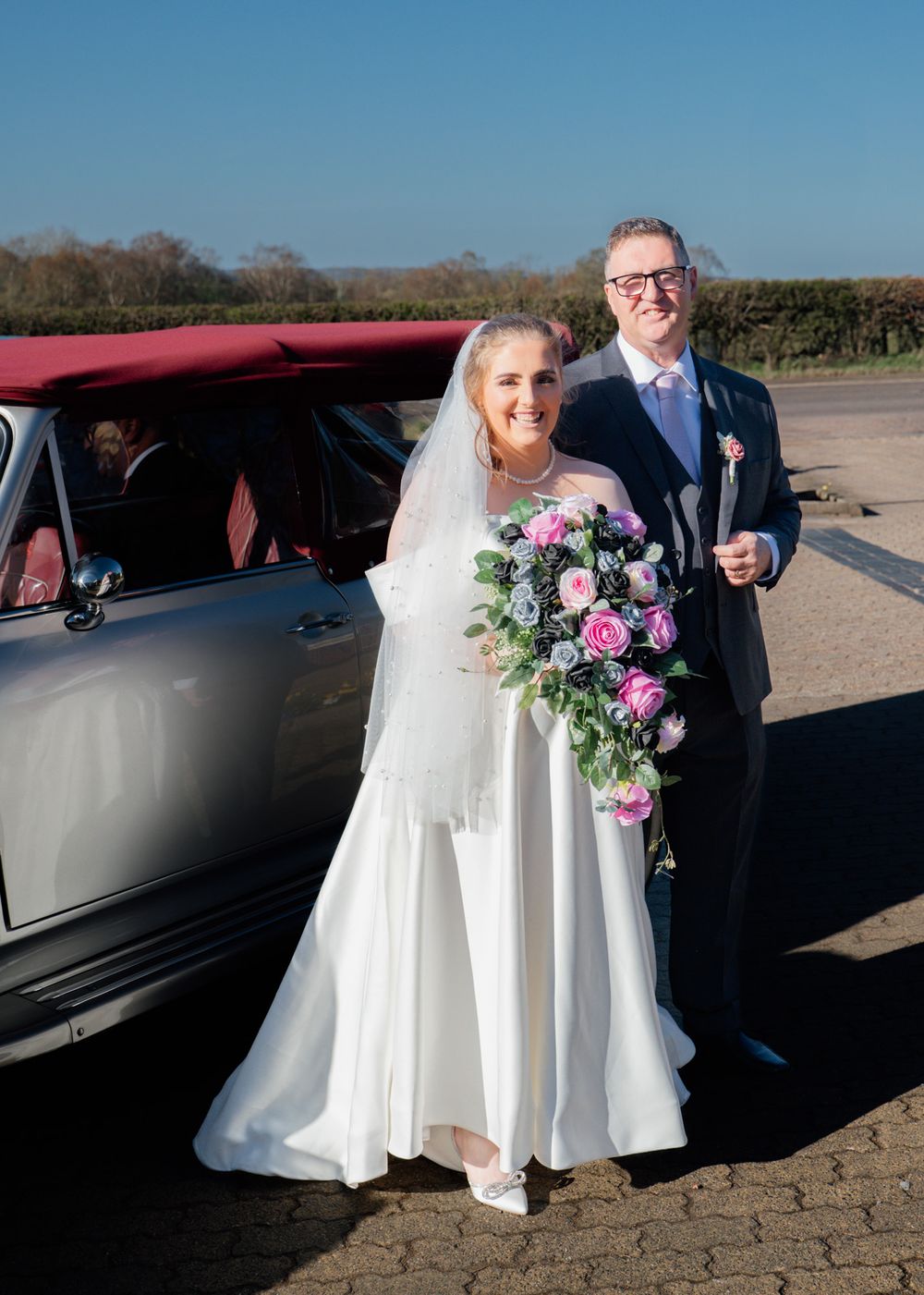 Wedding party arriving at venue in black limousine with pink and purple floral bouquets.