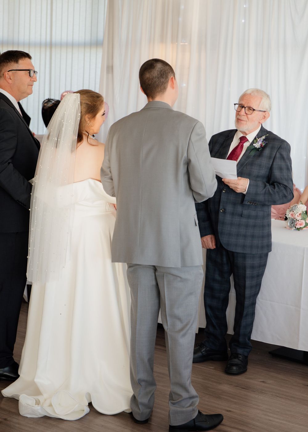 Wedding party gathering in elegant indoor venue with white walls and hardwood floors.