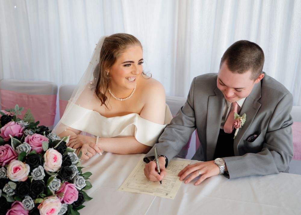 Couple sharing candid moments at wedding reception with pink floral decorations.