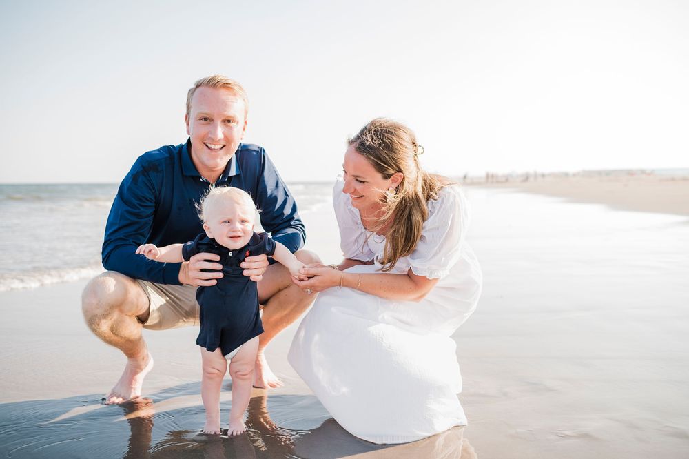 Happy family of three plays and smiles while spending time together on a sunny beach.
